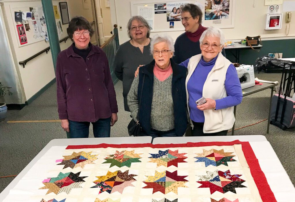 people standing in front of a quilt
